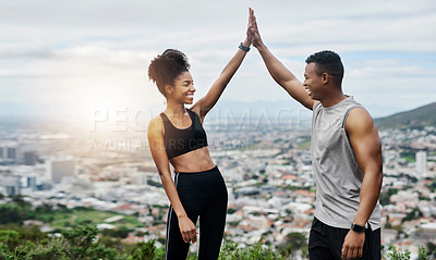 Buy stock photo Shot of a sporty young couple high fiving each other while exercising outdoors