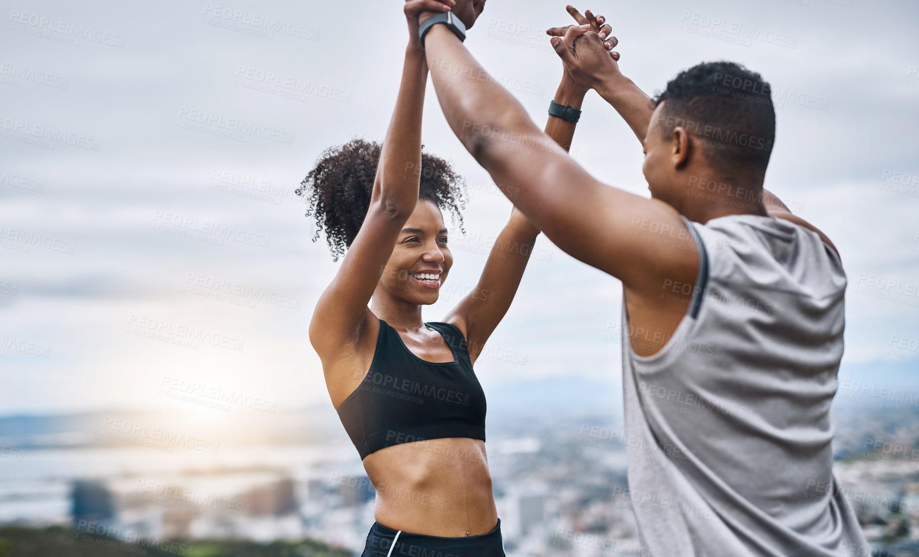 Buy stock photo Shot of a sporty young couple high fiving each other while exercising outdoors