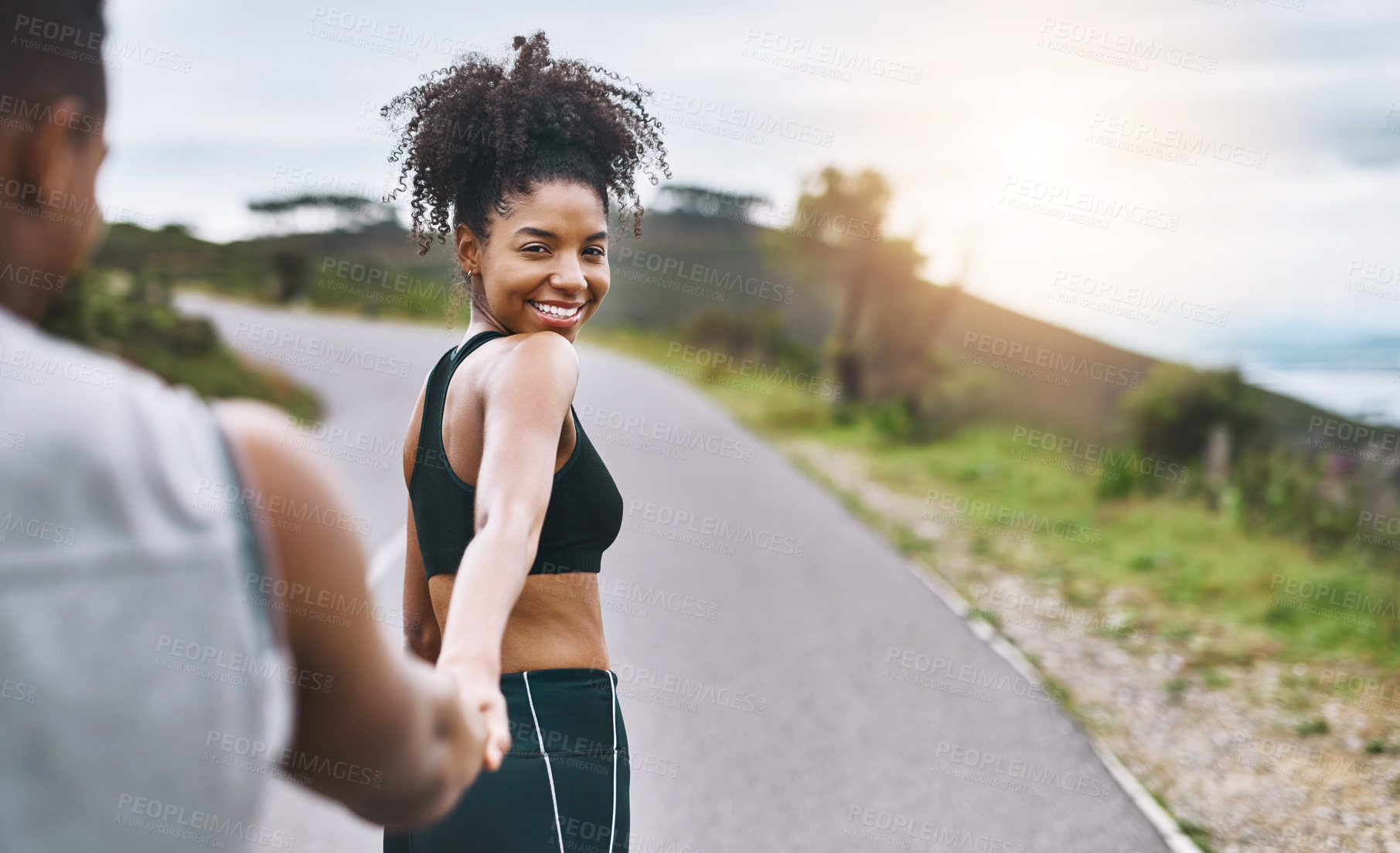 Buy stock photo Portrait of a sporty young woman leading her partner by the hand while exercising outdoors