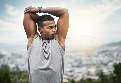 Buy stock photo Shot of a sporty young man stretching his arms while exercising outdoors
