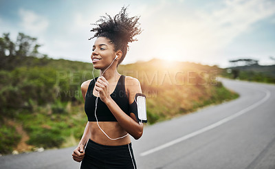 Buy stock photo Fitness, sports and happy woman running in a road with music for health, workout or cardio routine. Smile, exercise and African female runner in nature with podcast for training, motivation or energy