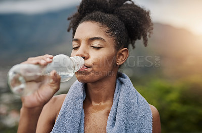 Buy stock photo Shot of a sporty young woman drinking water while exercising outdoors