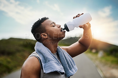 Buy stock photo Shot of a sporty young man drinking water while exercising outdoors