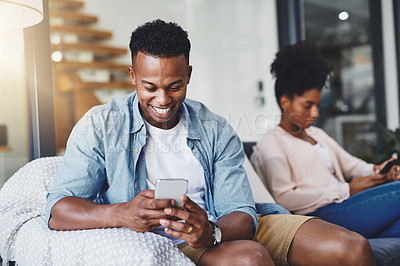 Buy stock photo Shot of a young couple using their mobile phones on the sofa at home