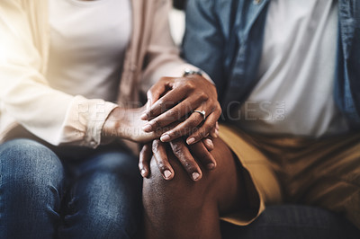 Buy stock photo Cropped shot of a man and woman sitting on a sofa and holding hands