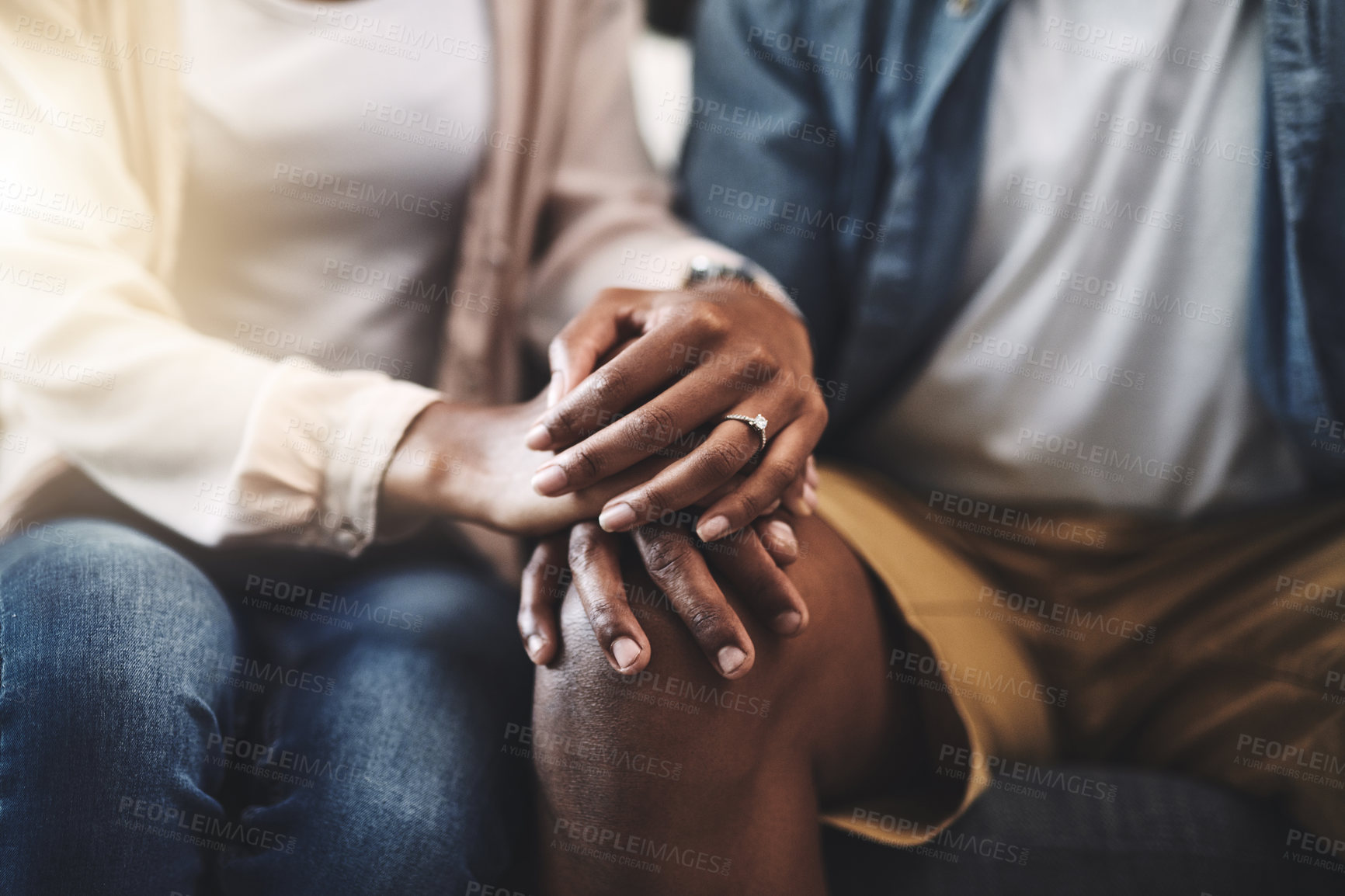 Buy stock photo Cropped shot of a man and woman sitting on a sofa and holding hands
