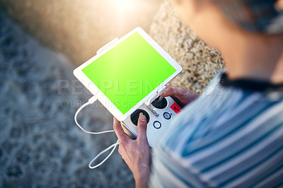 Buy stock photo Closeup of an unrecognizable man holding a remote control and using it to fly a drone outside on a beach during the day