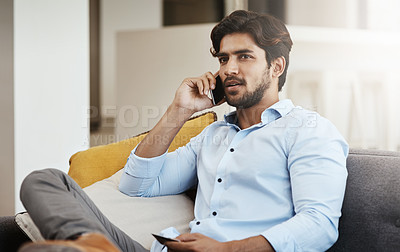 Buy stock photo Cropped shot of a handsome young man making a phonecall while shopping online on his sofa in the living room at home