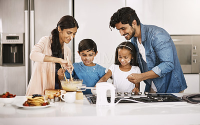 Buy stock photo Cropped shot of an affectionate young family cooking breakfast in their kitchen at home