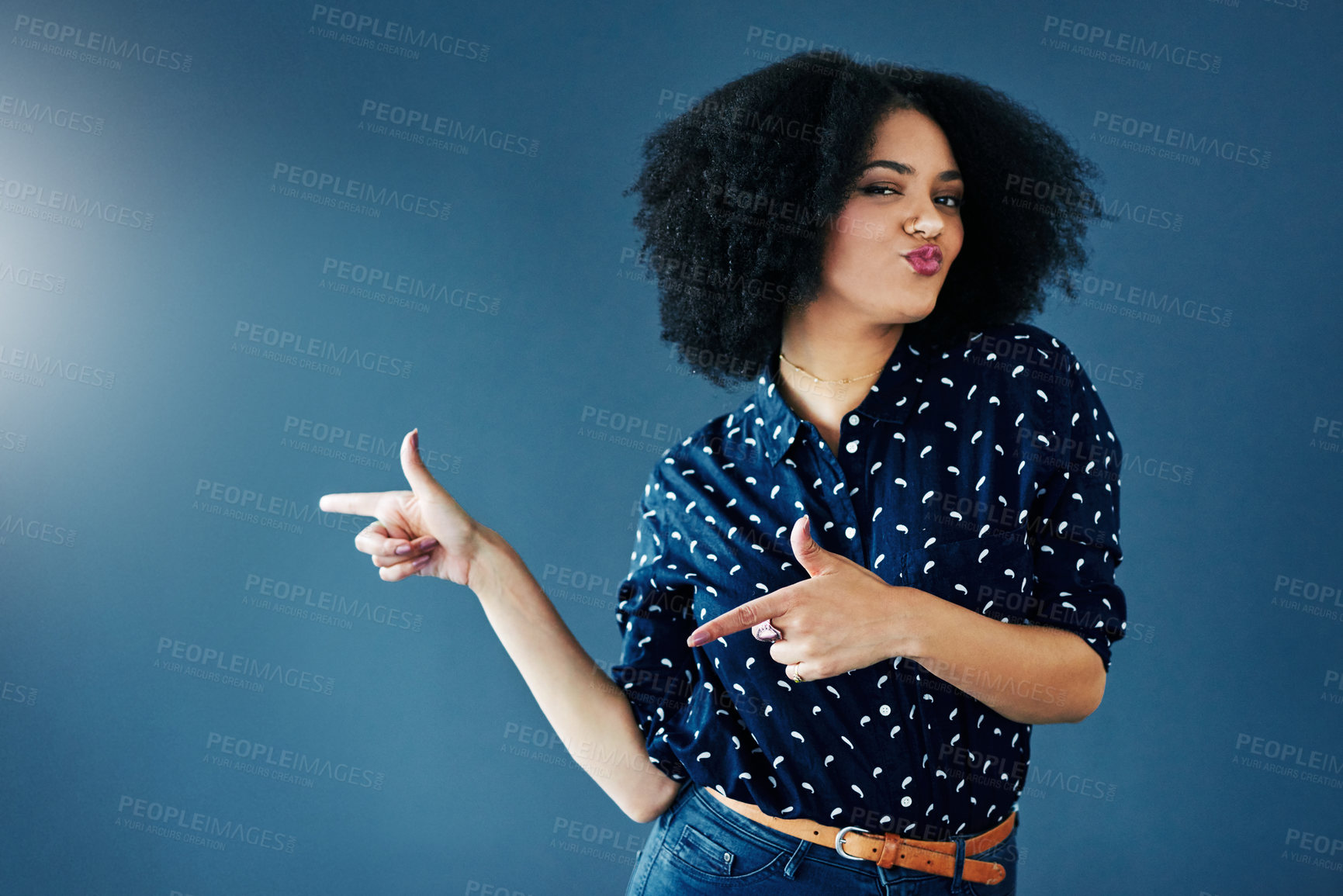 Buy stock photo Studio shot of a young woman gesturing towards copy space against a blue background