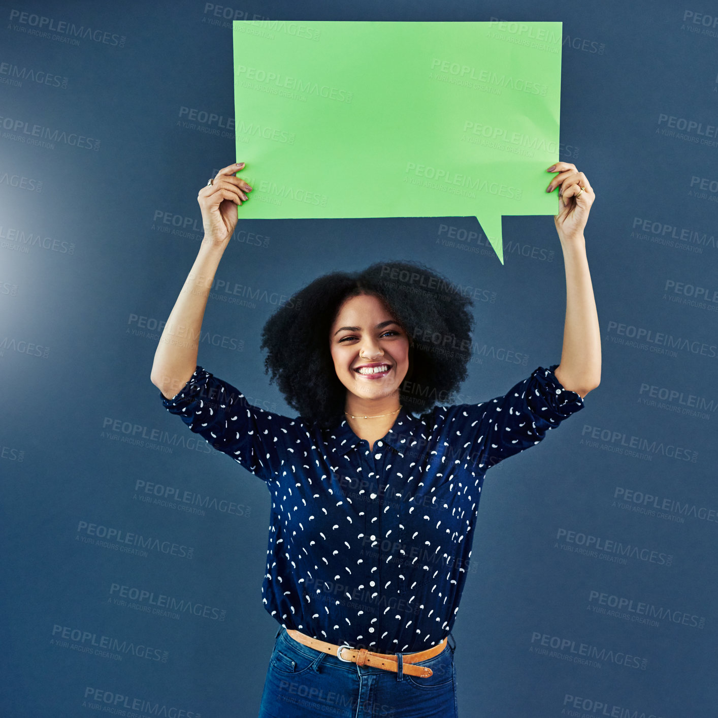 Buy stock photo Studio shot of a young woman holding up a blank speech bubble against a blue background