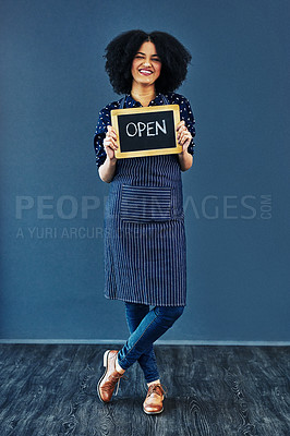Buy stock photo Studio shot of a young woman holding a chalkboard with the word “open” on it against a blue background