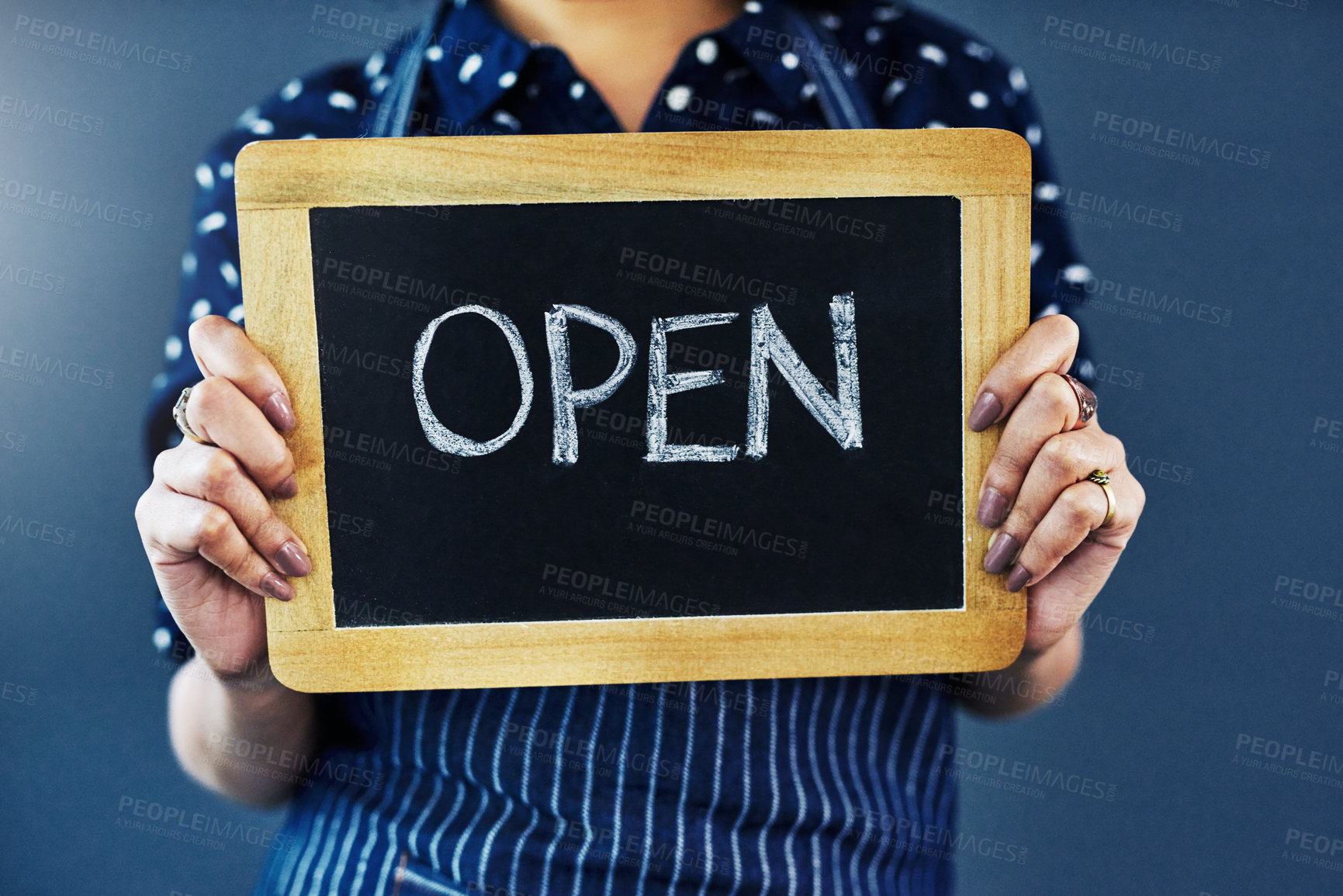 Buy stock photo Cropped studio shot of a woman holding a chalkboard with the word “open” on it against a blue background
