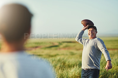 Buy stock photo Shot of father throwing a football to his son on a field
