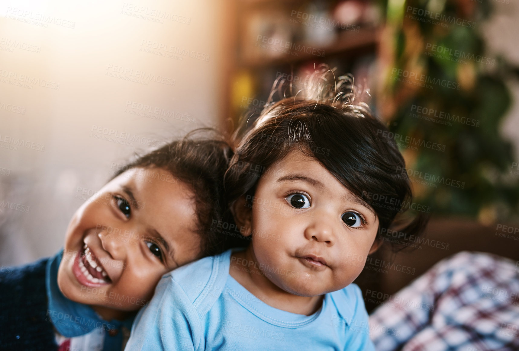 Buy stock photo Portrait of a cheerful little baby boy and his older sister relaxing at home while looking into the camera inside during the day