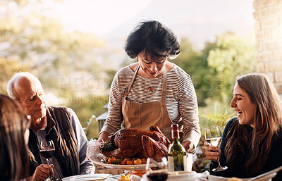 Buy stock photo Cropped shot of a mature woman bringing a freshly cooked turkey to the dining table on Thanksgiving