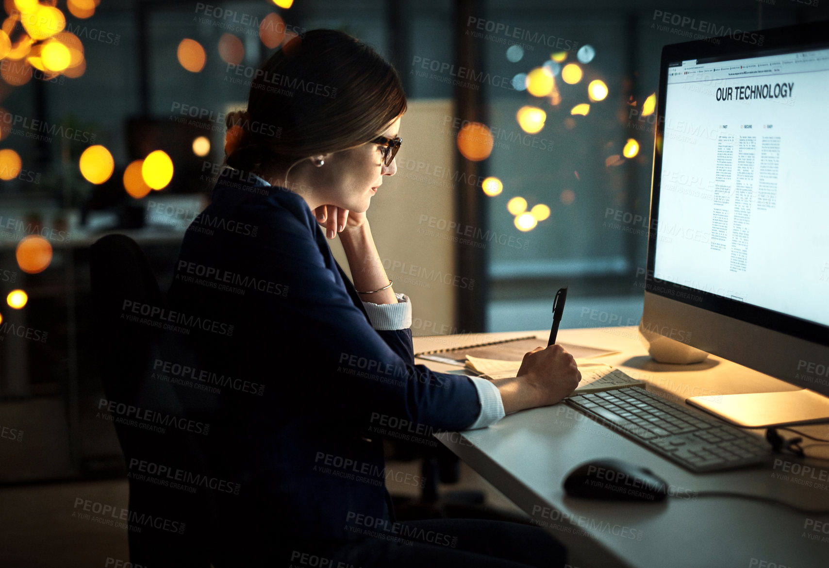 Buy stock photo Shot of a young businesswoman writing notes while working late in an office