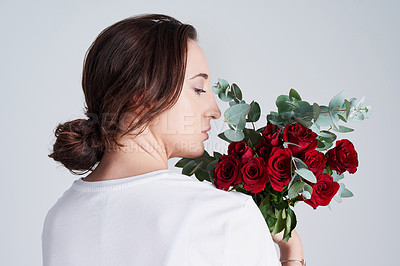 Buy stock photo Studio shot of a young woman smelling a bunch of roses
