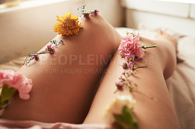 Buy stock photo Shot of an unidentifiable young woman lying in bed with flowers arranged on her legs