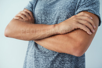 Buy stock photo Closeup shot of an unrecognizable man standing with his arms crossed against a grey background