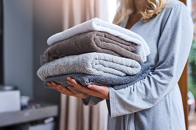 Buy stock photo Laundry, cleaning and a woman with a stack of towels in her home for hygiene or a spring clean day. Housework, housewife and a female person carrying a pile of fresh or soft fabric in a living room