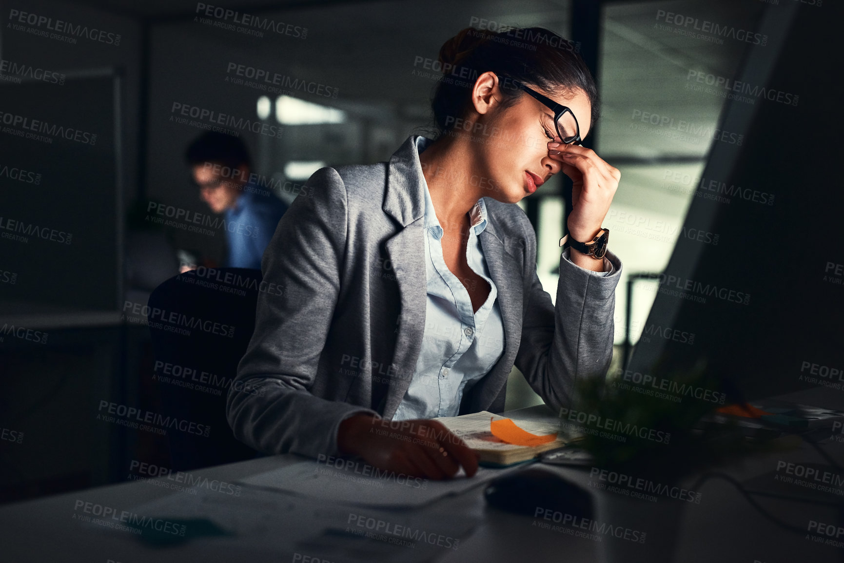 Buy stock photo Stressed business woman working late on a computer in an office at night. Young worried entrepreneur feeling tired while struggling with burnout, eye strain and a headache from deadlines and pressure