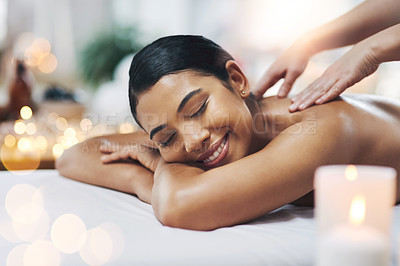 Buy stock photo Shot of a relaxed an cheerful young woman getting a massage indoors at a spa