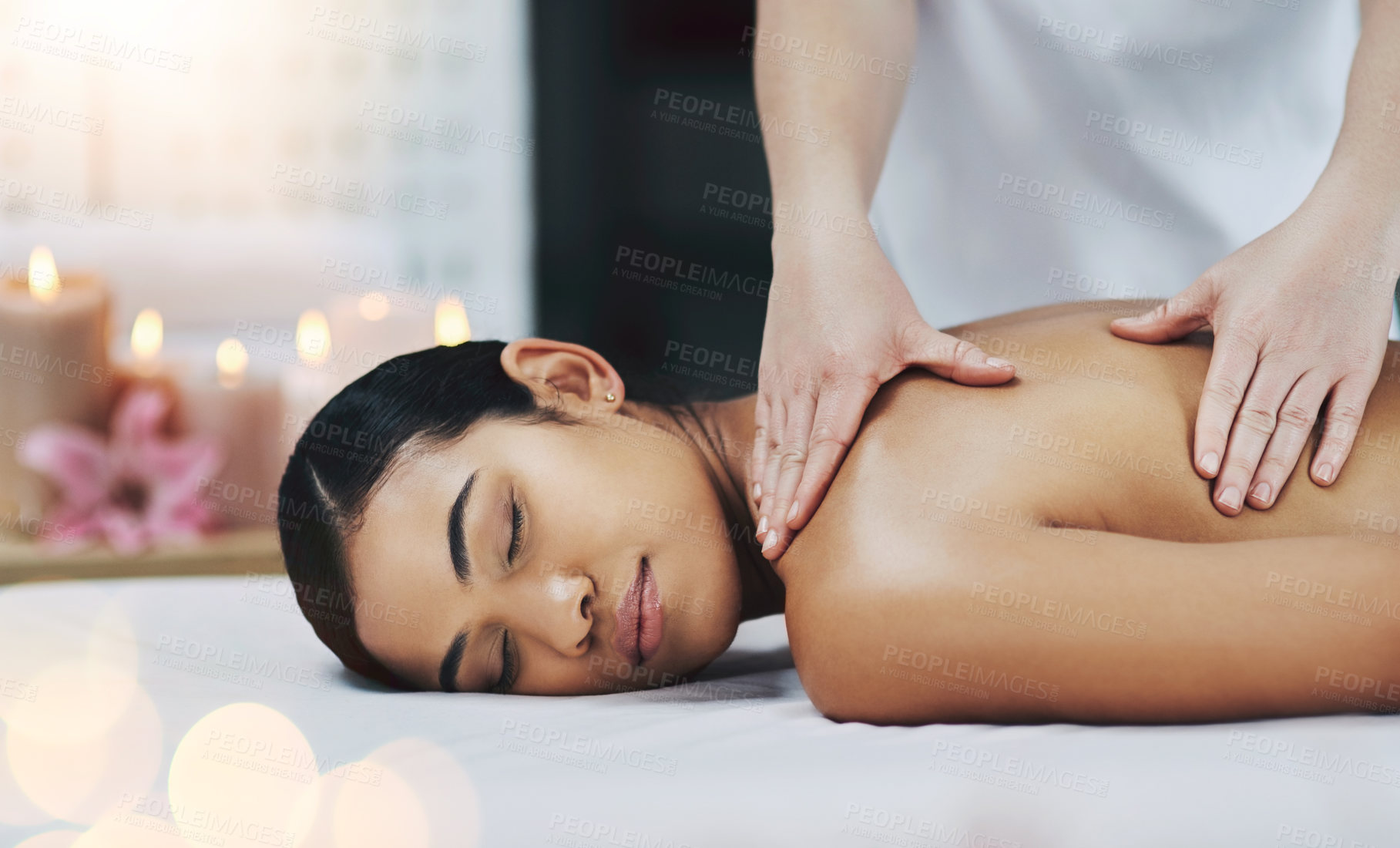 Buy stock photo Shot of a relaxed an cheerful young woman getting a massage indoors at a spa