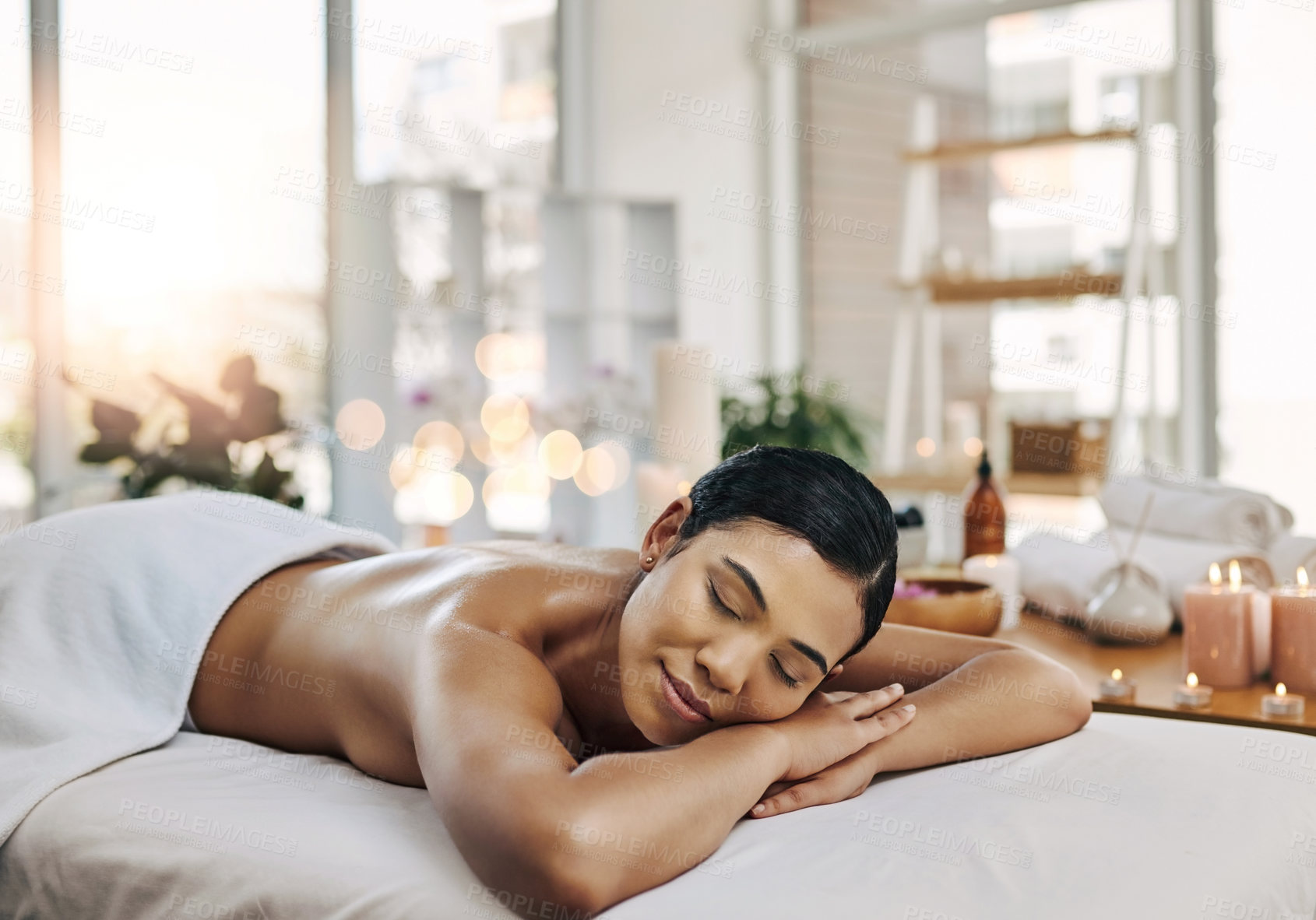 Buy stock photo Shot of a relaxed an cheerful young woman getting a massage indoors at a spa