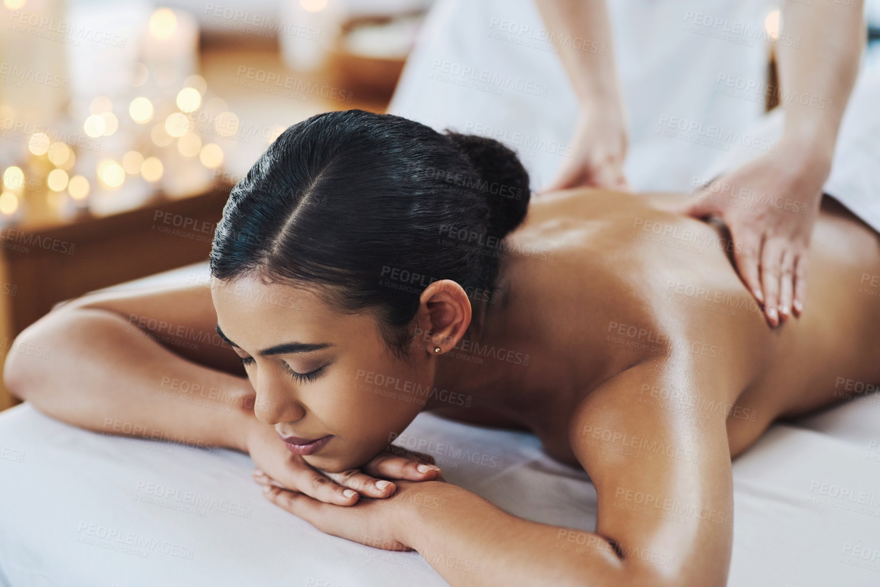 Buy stock photo Shot of a relaxed an cheerful young woman getting a massage indoors at a spa