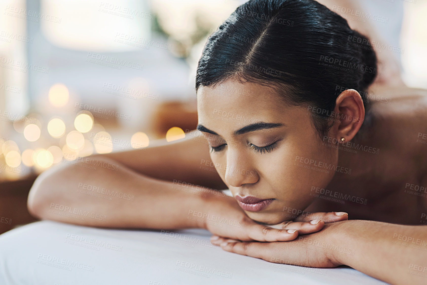 Buy stock photo Shot of a relaxed an cheerful young woman getting a massage indoors at a spa