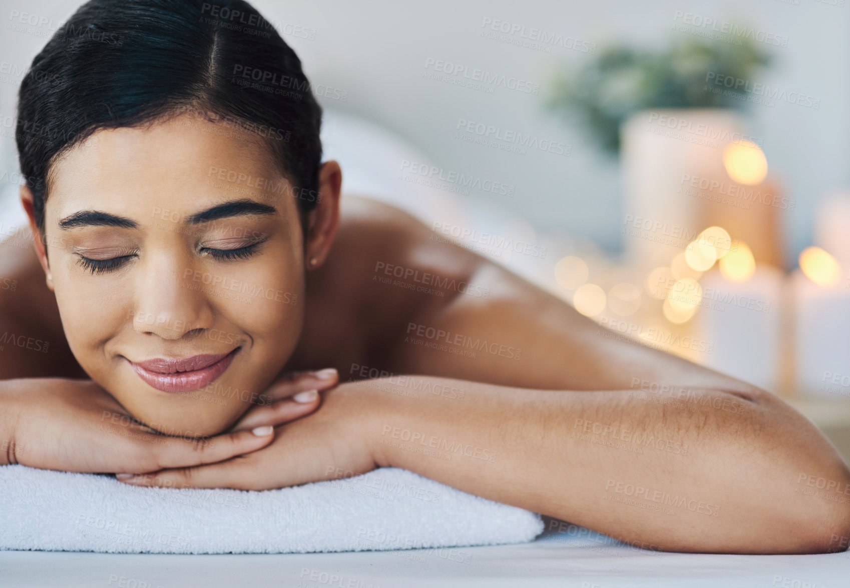 Buy stock photo Shot of a relaxed an cheerful young woman getting a massage indoors at a spa