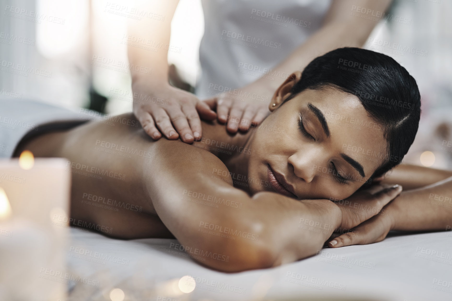 Buy stock photo Shot of a relaxed an cheerful young woman getting a massage indoors at a spa