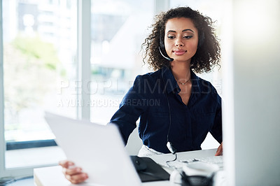 Buy stock photo Cropped shot of an attractive young female call center agent reading some paperwork while working in her office