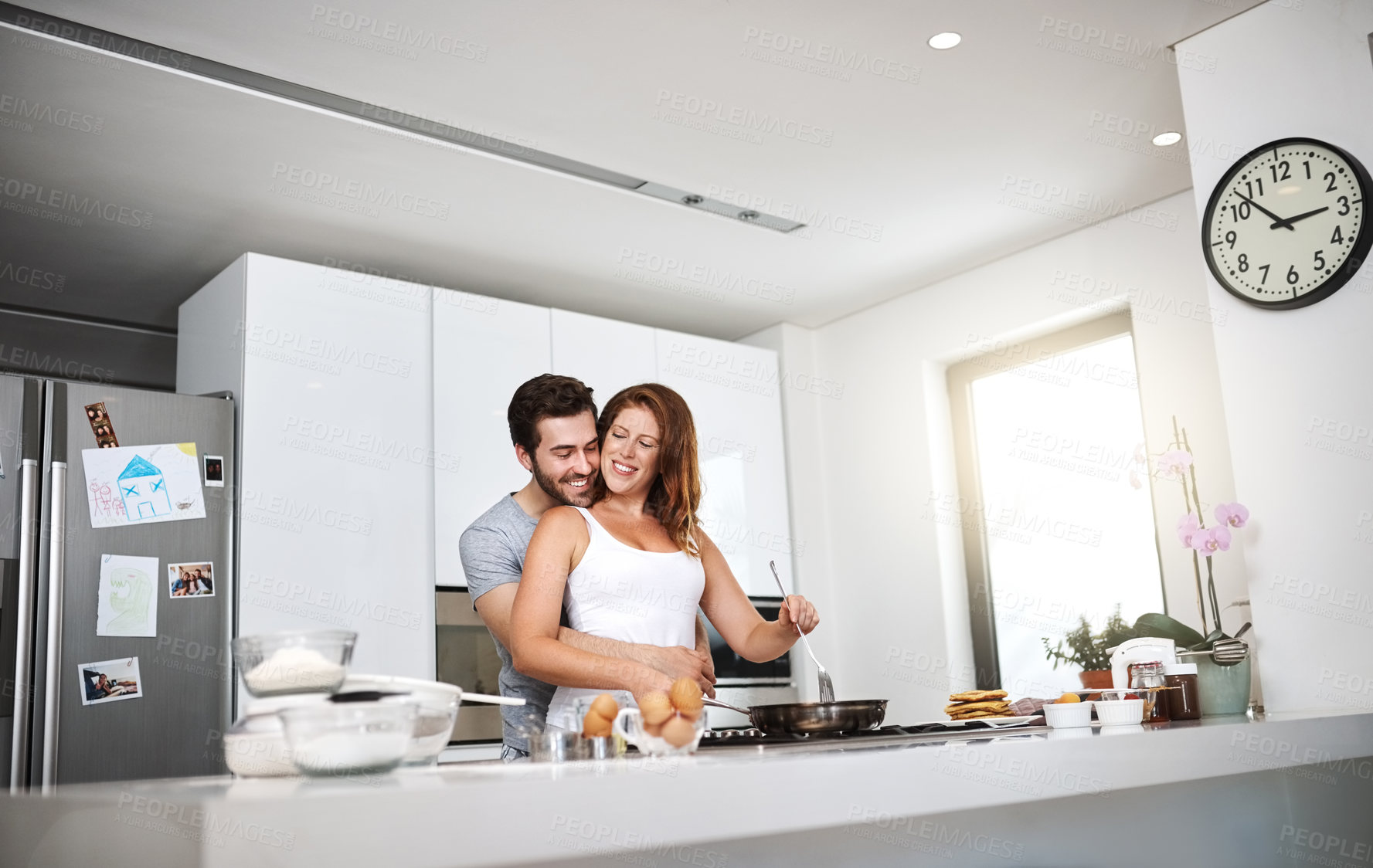 Buy stock photo Shot of a happy young couple preparing breakfast in the morning