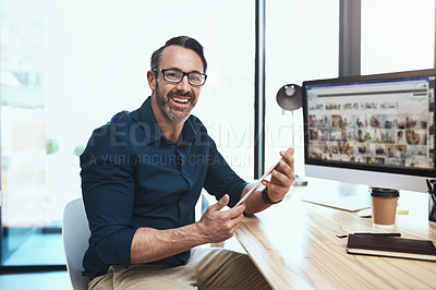Buy stock photo Shot of a mature businessman using his digital tablet while sitting at his desk