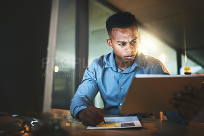 Buy stock photo Cropped shot of a handsome young businessman using his tablet while working late at night in a modern office