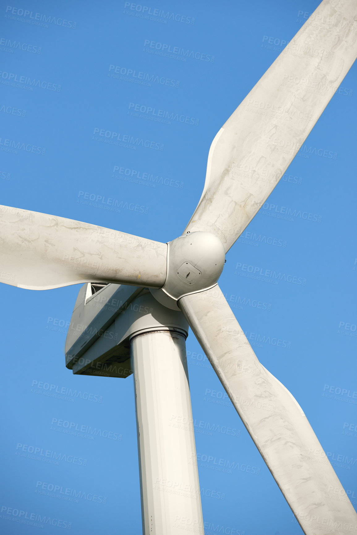 Buy stock photo A wind turbine and rotor blades isolated against a blue sky on a sustainable, eco friendly farm. Low angle view of harvesting a biodegradable energy source to generate electricity from windy climates