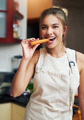Buy stock photo Cropped portrait of an attractive young woman taking a bite of a carrot at home