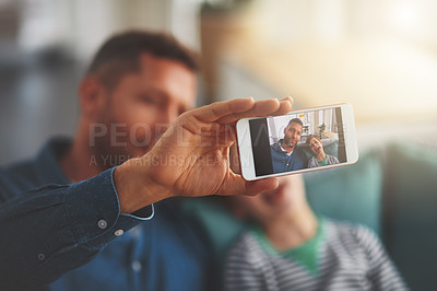 Buy stock photo Closeup of a cheerful little boy and his father taking a self portrait together while being seated on the sofa together