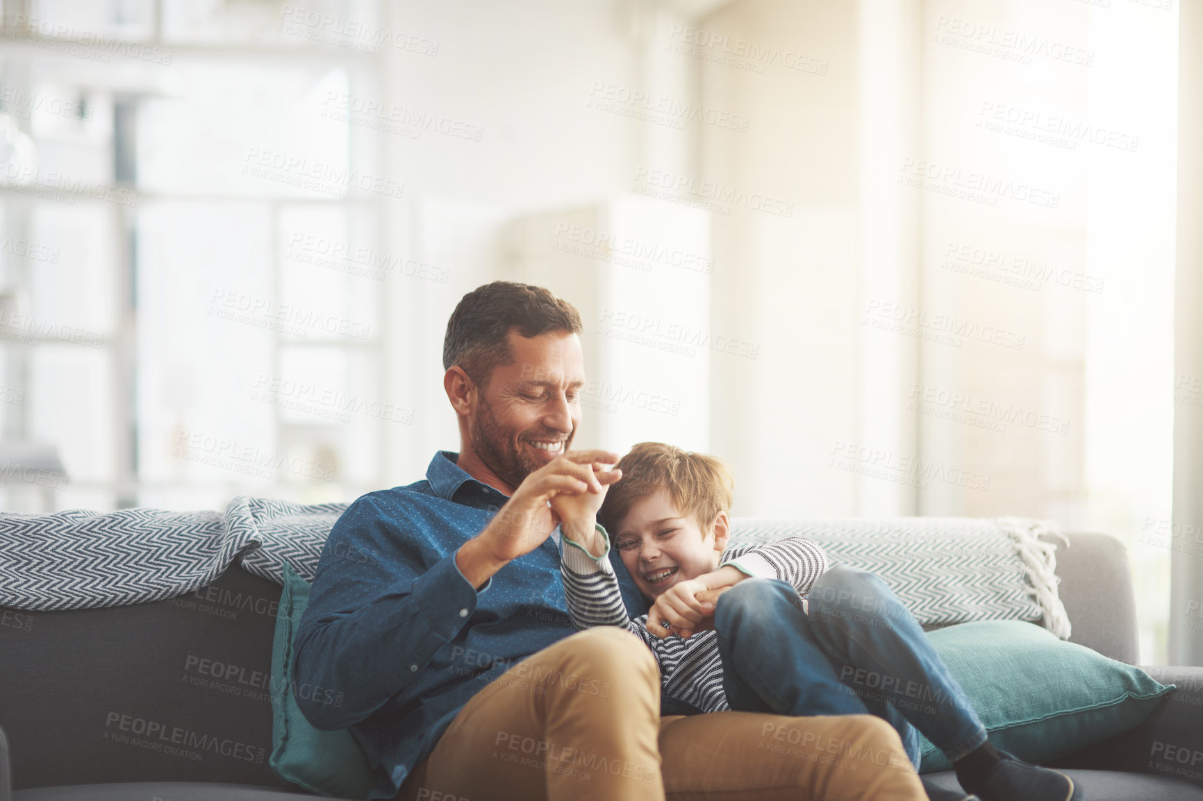 Buy stock photo Father, boy and laughing on couch together in home, bonding and hug for funny conversation. Daddy, son and happy family playing in living room for joke, talk and embrace for security in relationship