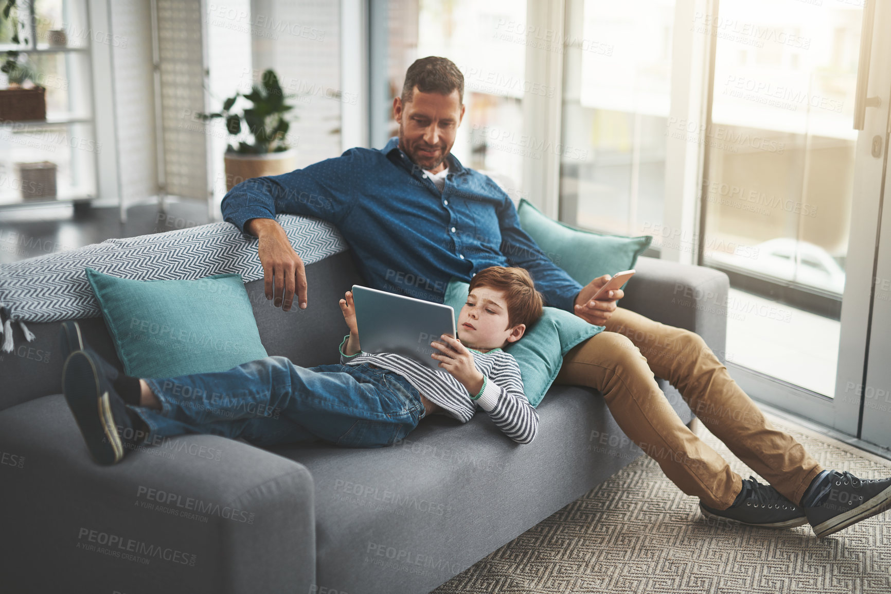 Buy stock photo Man, relax and kid with tablet on sofa for online entertainment, network and bonding together. Family, home and son with tech by father for internet, connection and download of game in living room