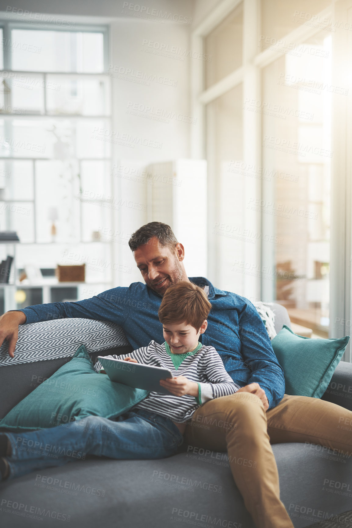 Buy stock photo Happy, man and son with tablet on sofa for online movie, bonding or entertainment together. Family, home and child with tech by dad for film streaming, connectivity or watching cartoon in living room