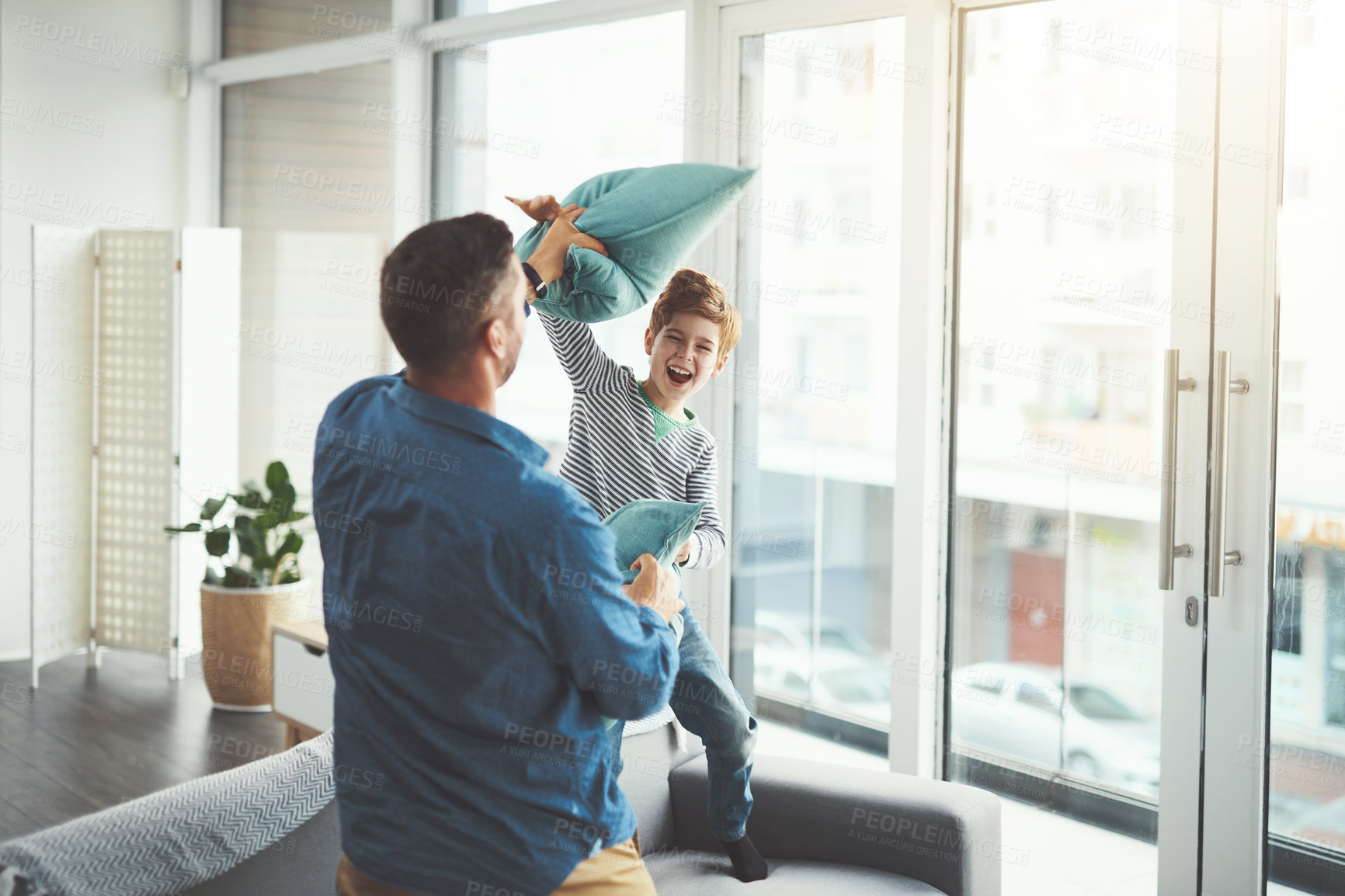 Buy stock photo Pillow fight, happy and dad with child on sofa for bonding, relationship and relax in living room. Family, home and father and young boy having fun for energy, playing together and games on couch