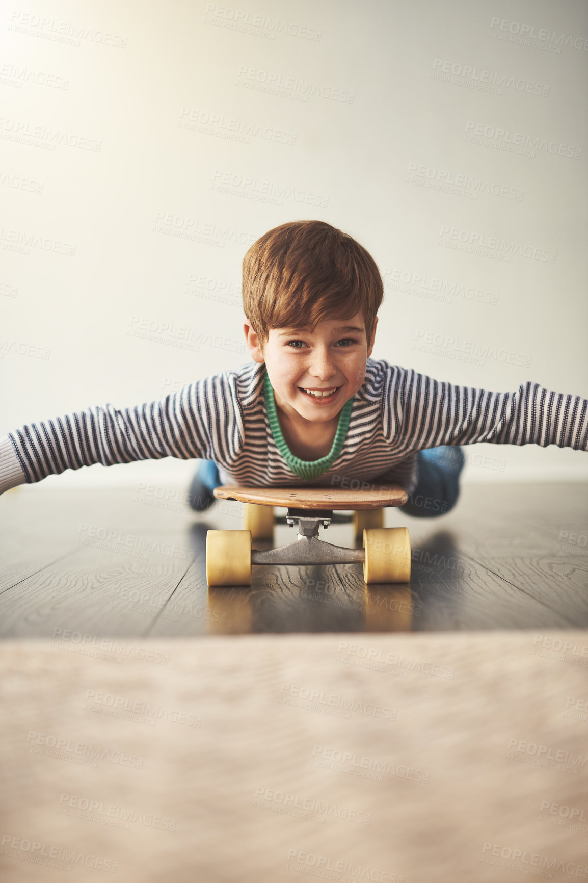 Buy stock photo Portrait, child and skateboard in home for relax, airplane and balance development for fun. Young boy, longboard and happy in living room for game, growth and playful on floor and learning to ride