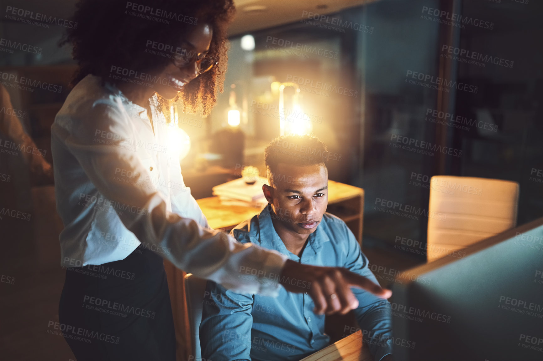 Buy stock photo Shot of two businesspeople working together on a computer in an office at night