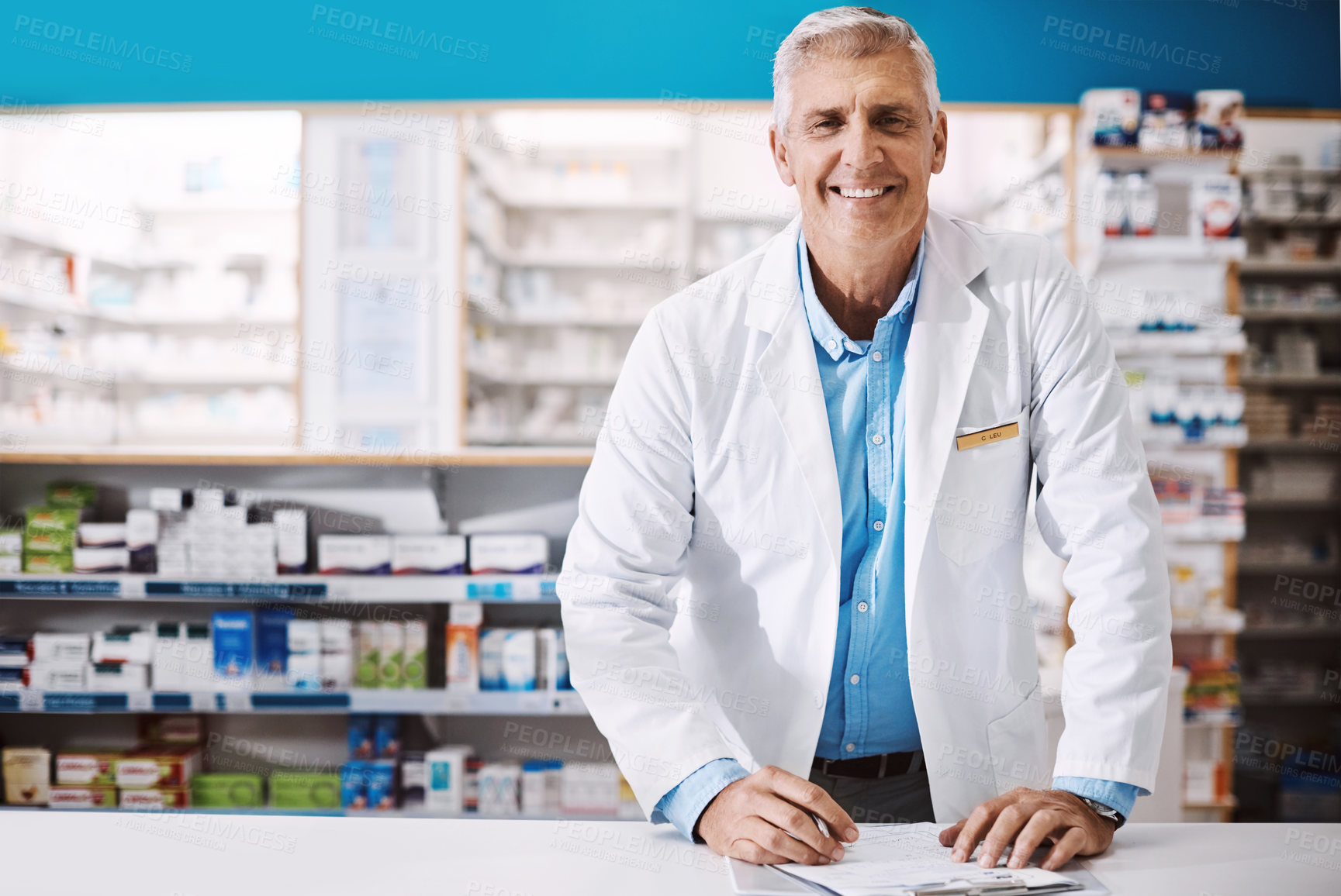 Buy stock photo Shot of a male pharmacist writing on a clipboard in a drugstore