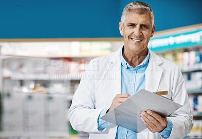 Buy stock photo Shot of a male pharmacist writing on a clipboard in a drugstore
