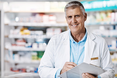 Buy stock photo Shot of a male pharmacist writing on a clipboard in a drugstore