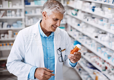 Buy stock photo Shot of a pharmacist reading the label on a product in a drugstore